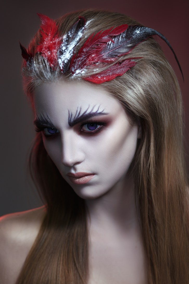 мода beauty portrait of a girl with dark make-up and creative hairstyle with feathers.