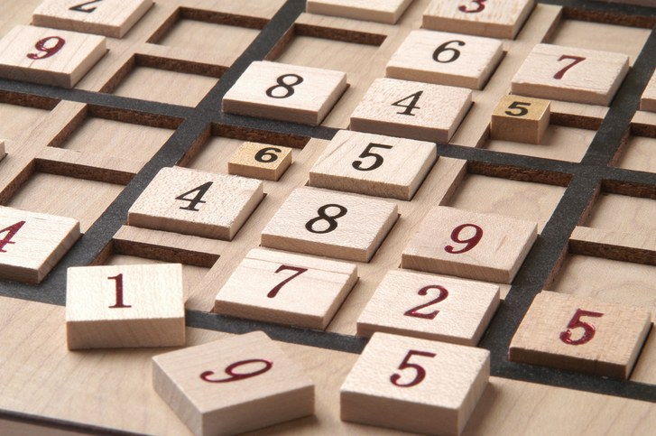 Eine Fotografie eines hölzernen Sudoku-Puzzlebrettes mit den Zahlen schief und außer Betrieb