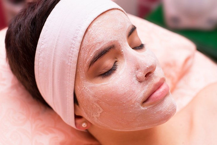 жена wearing exfoliating face mask at spa